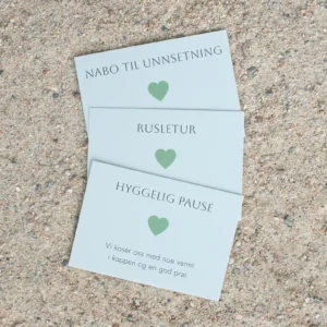 Tre grønne hjertelapper med teksten “Nabo til unnsetning”, “Rusletur” og “Hyggelig pause”, liggende på sand. Hver lapp har et grønt hjerte og enkel, sort tekst.