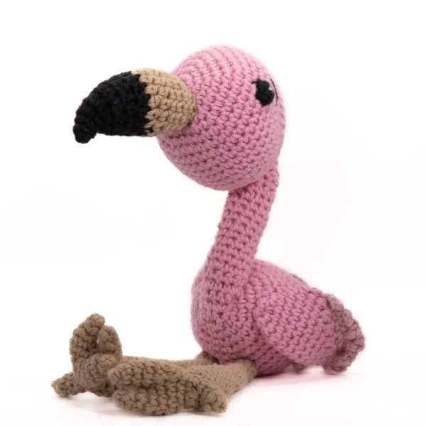 Håndlaget heklet flamingo i rosa og beige garn med svart nebb – kjent som Frida Flamingo, en hjertevenn med lange bein og sjarmerende stil.
