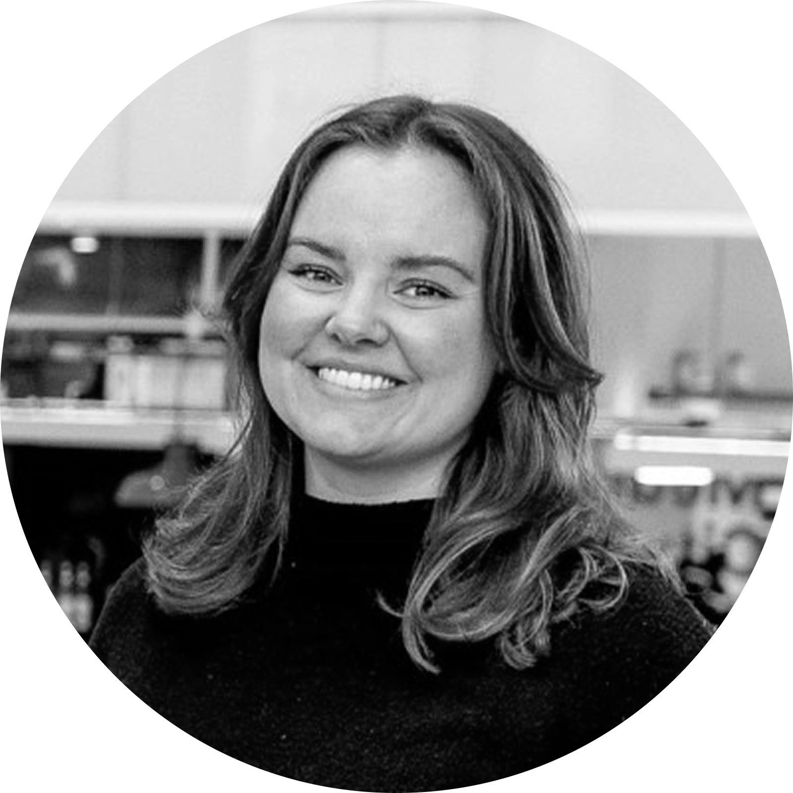 Portrett av en smilende kvinne med skulderlangt hår, fotografert innendørs i svart-hvitt.
