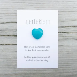 Blå hjerteklem fra oss – et lite hjerte på kort med teksten «Her er en hjerteklem som du kan ha i lommen din. En liten påminnelse om at vi alltid er her for deg.»
