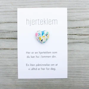 Fargerik hjerteklem fra oss – et lite hjerte på kort med teksten «Her er en hjerteklem som du kan ha i lommen din. En liten påminnelse om at vi alltid er her for deg.»