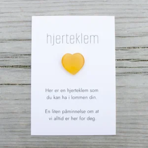 Gul hjerteklem fra oss – et lite hjerte på kort med teksten «Her er en hjerteklem som du kan ha i lommen din. En liten påminnelse om at vi alltid er her for deg.»